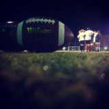 In primo piano, un pallone da football americano. Poco lomtano, le ragazze in cerchio si danno la carica