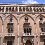 La facciata esterna di palazzo Fizzarotti divisa in cinque campate, con arcate ogivali e medaglioni nelle intersecazioni e chiusa da due torrette
