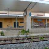 L'interno spettrale della stazione tra vegetazione spontanea, scritte sui muri e il cartello che indica la fermata "Sannicandro di Bari" ancora presente