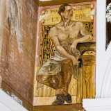 Sulla sinistra � disegnato un fabbro: una baffuta figura maschile a torso nudo, seduta vicino a un�incudine e con in mano un martello. Presenta la scritta labor omnia vincit (�la fatica vince ogni cosa�)
