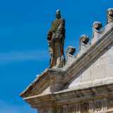 Il prospetto termina con un�ampia quinta triangolare: sui tre vertici sono collocate delle sculture in pietra raffiguranti San Pietro e San Paolo ai lati...