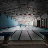 Ci immettiamo in un corridoio che conduce al lato opposto del complesso, laddove finalmente possiamo ammirare la piscina, ormai priva della sua essenza idrica, immersa in un silenzio irreale
