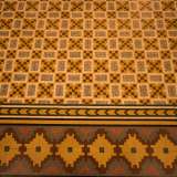 Per terra, in parte celato dal tavolo ovale in legno, ammiriamo l�antico pavimento perfettamente conservato: riproduce diverse forme geometriche multicolori