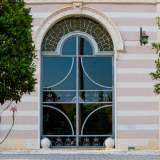 Una frase che ci invita ad entrare varcando il notevole portone in vetro, che si contraddistingue per il profilo curvilineo delle ante battenti e per il sopraluce a forma di arco di corona circolare