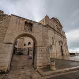 Alla sinistra dell�ingresso della chiesa notiamo un�arcata in pietra con un bassorilievo della Madonna, quella che introduce all�ex cortile dei pellegrini