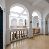 Raggiungiamo quindi l�ultimo piano attraverso un�altra scala interna. Spessi pilastri bianchi che reggono candidi archi segnano il profilo del lungo corridoio...