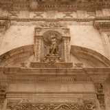 Il tutto � sormontato da un architrave con il timpano interrotto da una nicchia che racchiude la statua dell'Arcangelo Gabriele, attorniato naturalmente da teschi e ossa
