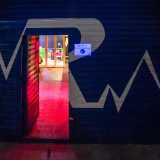 ...per ritrovarsi davanti a una serranda blu con una grande R bianca al centro illuminata da un piccolo neon