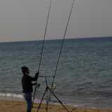 Un pescatore impegnato a montare una canna da pesca