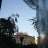 La facciata vista attraverso la recinzione. Al centro la grossa palma divorata dal punteruolo rosso