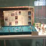 Un album di figurine stampato negli anni 70 posto dietro il microcalcio, una specie di Subbuteo del 1950 in cui i giocatori vengono mossi con delle manopole installate dietro le porte