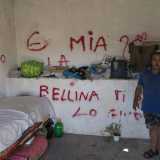 In una stanza sono accatastati tutti i suoi vestiti. C�� un letto e sparse qui e l� delle damigiane in plastica con pochissima acqua recuperata da una fontana pubblica che si trova nelle vicinanze. I muri sono tutti pieni di scritte, tra parolacce e dediche d�amore