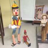 Due esemplari di Pinocchio accanto a un cavallo a dondolo