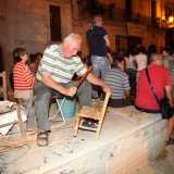 Gaetano con un piccolo bastone che picchia sulla sedia a lavoro finito per rendere la seduta pi� stabile