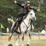 Un arciere a cavallo con in mano un arco mediorientale durante una sessione di caccia