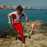 Un giovane atleta, dopo aver marcato il cartellino nei pressi della lanterna,  riparte velocemente per raggiungerne un'altra. La gara si svolge sulla costa