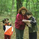 Una donna e due bambini, probabilmente madre e figli, fermi a un punto di controllo consultano la mappa