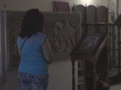 Una fedele prega accanto all'antico bassorilievo collocato anticamente nell'altare maggiore