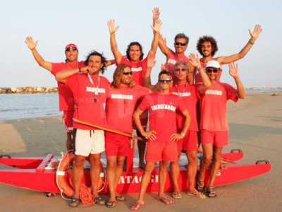 Un gruppo di bagnini sulla spiaggia con la barca a remi e il salvagente di salvataggio 