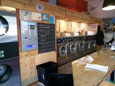 Un prezzario e delle lavatrici a gettoni all'interno della lavanderia automatica di via Crisanzio