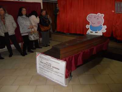 I fedeli entrano nella stanza e trovano una bara chiusa sormontata da un cartoncino che raffigura Peppa Pig