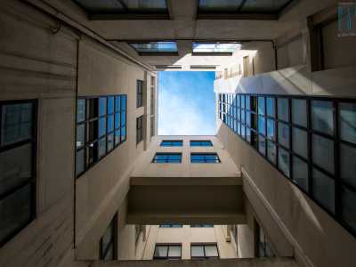  Una porta a vetri nasconde un piccolo cortile illuminato da un pozzo luce che permette di seguire lo sviluppo verso l�alto del fabbricato, con i blocchi di cemento ingentiliti dal riflesso del cielo terso sulle vetrate