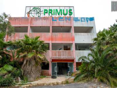 Ci ritroviamo cos� davanti a un fabbricato quadrato di tre piani di colore bianco e rosso sbiadito circondato da palme rigogliose ma non curate. Sul tetto svetta l�insegna verde e arancione: l�unico elemento rimasto ancora intatto