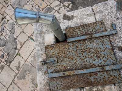 Di forma quadrata, in muratura bianca e alto circa un metro rispetto al livello stradale, risulta coperto da una lastra di ferro bloccata da un lucchetto