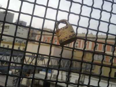 Un lucchetto dell'amore agganciato alla rete metallica del ponte pedonale 