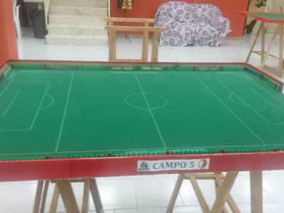Un campo da gioco di Subbuteo con mini cartelli pubblicitari, recinzioni e alcuni tifosi