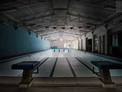 Ci immettiamo in un corridoio che conduce al lato opposto del complesso, laddove finalmente possiamo ammirare la piscina, ormai priva della sua essenza idrica, immersa in un silenzio irreale
