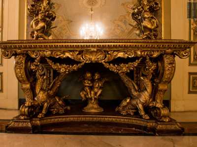...raccolti in cornici sfarzose e dorate e poggiati su una consolle in marmo e legno intagliato