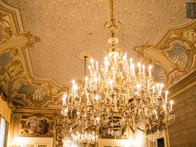 ...e dai due lampadari di cristallo. Questi ultimi pendono da un soffitto con motivo a intreccio e putti che sorreggono vari stemmi