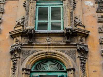 ...mentre nella parte superiore la trabeazione con fregio a rosette sorregge una mensola, su cui si apre una nuova finestrella