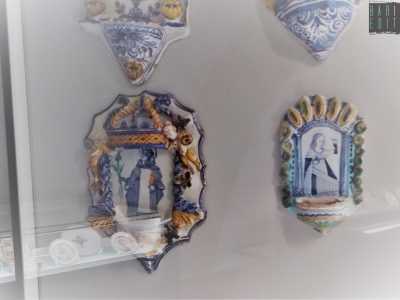 Avvistiamo poi un'altra acquasantiera realizzata da Angelo Antonio D'Alessandro, uno dei pi� grandi maestri che Laterza abbia mai avuto, vissuto a cavallo tra il 600 e il 700. L'opera (in basso a destra) ritrae una santa con in mano un libro e nell'altro un bicchiere