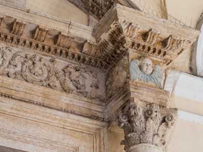 Sopra sono poggiati due blocchetti cubici disegnati con volti di angeli e cornicette dentellate