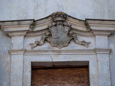 Pi� in alto fa bella mostra di s� uno scudo con una torre, tre leoni e tre stelle, sormontato da una corona: � lo stemma dei D�Amelj Melodia, fondatori del palazzo nei primi del 700