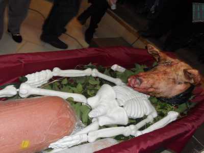 Tra le gambe dello scheletro c'� un grande pezzo di mortadella e sopra il collo spunta la testa di un maiale vero