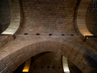 Qui su due file di possenti pilastri poggiano alti archi in pietra che reggono le volte a botte realizzate con conci locali, dividendo la sala in tre corridoi