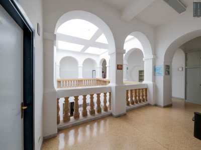 Raggiungiamo quindi l�ultimo piano attraverso un�altra scala interna. Spessi pilastri bianchi che reggono candidi archi segnano il profilo del lungo corridoio...