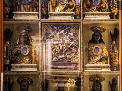 ...che comprende una teca dorata scandita in nove riquadri che contengono resti di santi. Ai busti neri con vesti d�oro di Olaro, Pio e Callisto seguono quelli di Lucia, Costanza, Cristoforo, Modesto e Carlo Borromeo...
