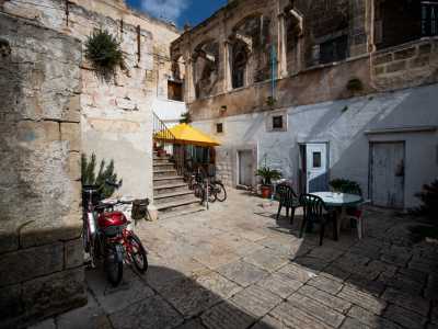 Quest�ultimo porta nella corte interna con pavimento a chianche dove tra biciclette, tavoli e sedie in plastica...
