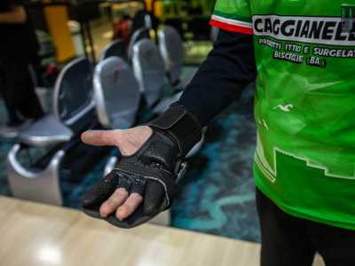 ...impugna la palla con un guanto utile a far aderire meglio le tre dita all�interno dei fori della boccia di colore giallo