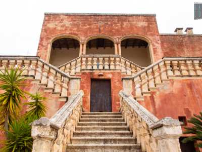 Una doppia e nobile scalinata delimitata da una serie di colonnine bianche conduce al piano nobile introdotto da un patio ad archi
