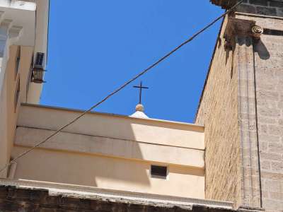 Alle spalle si intravede la punta del campanile sormontata dalla croce