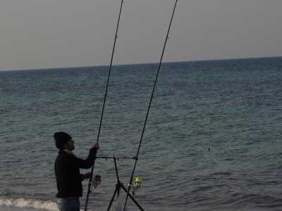 Un pescatore impegnato a montare una canna da pesca