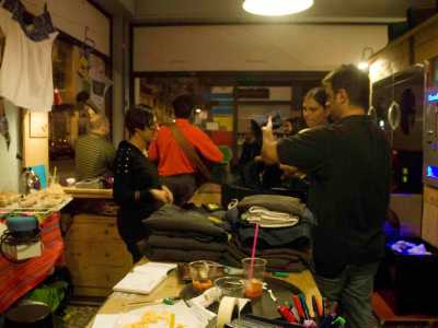 Alcuni clienti all'interno della lavanderia in via Dante. Sul tavolo cibo e bevande