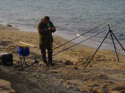 Un pescatore impegnato a montare le sue canne da pesca