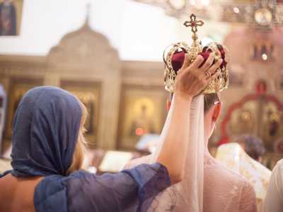 Una testimone aiuta la sposa a sorreggere l'imponente corona