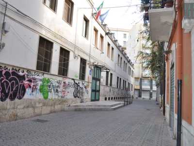 Salutiamo l�uomo per intraprendere via Fornari, la stradina pedonale che parte dalla piazzetta. La via � stretta a destra da un palazzo marrone e a sinistra dall�istituto comprensivo statale �Mazzini-Modugno�, la cui facciata � �colorata� da scritte e graffiti
